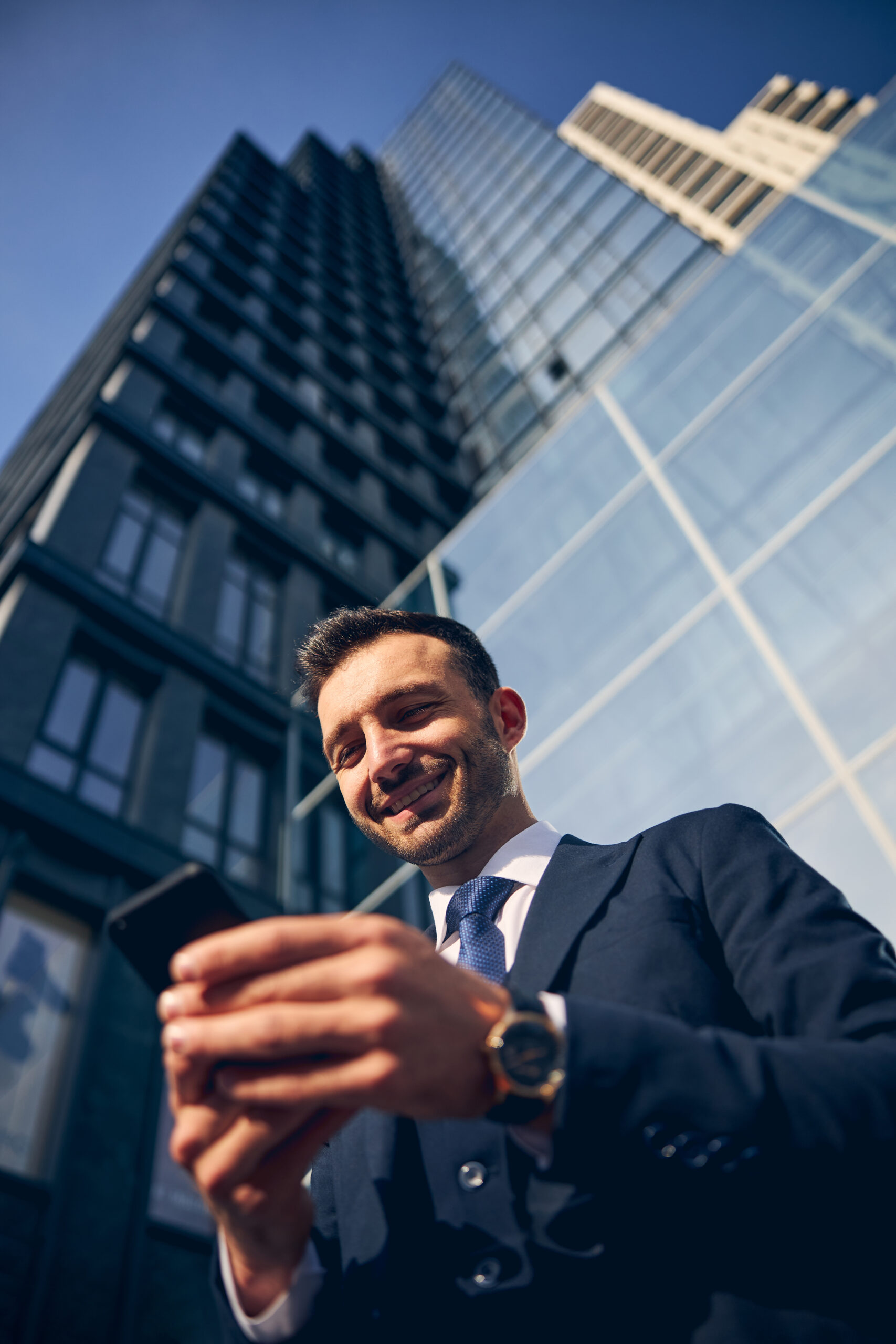 Handsome brunette businessman staying outside with mobile phone