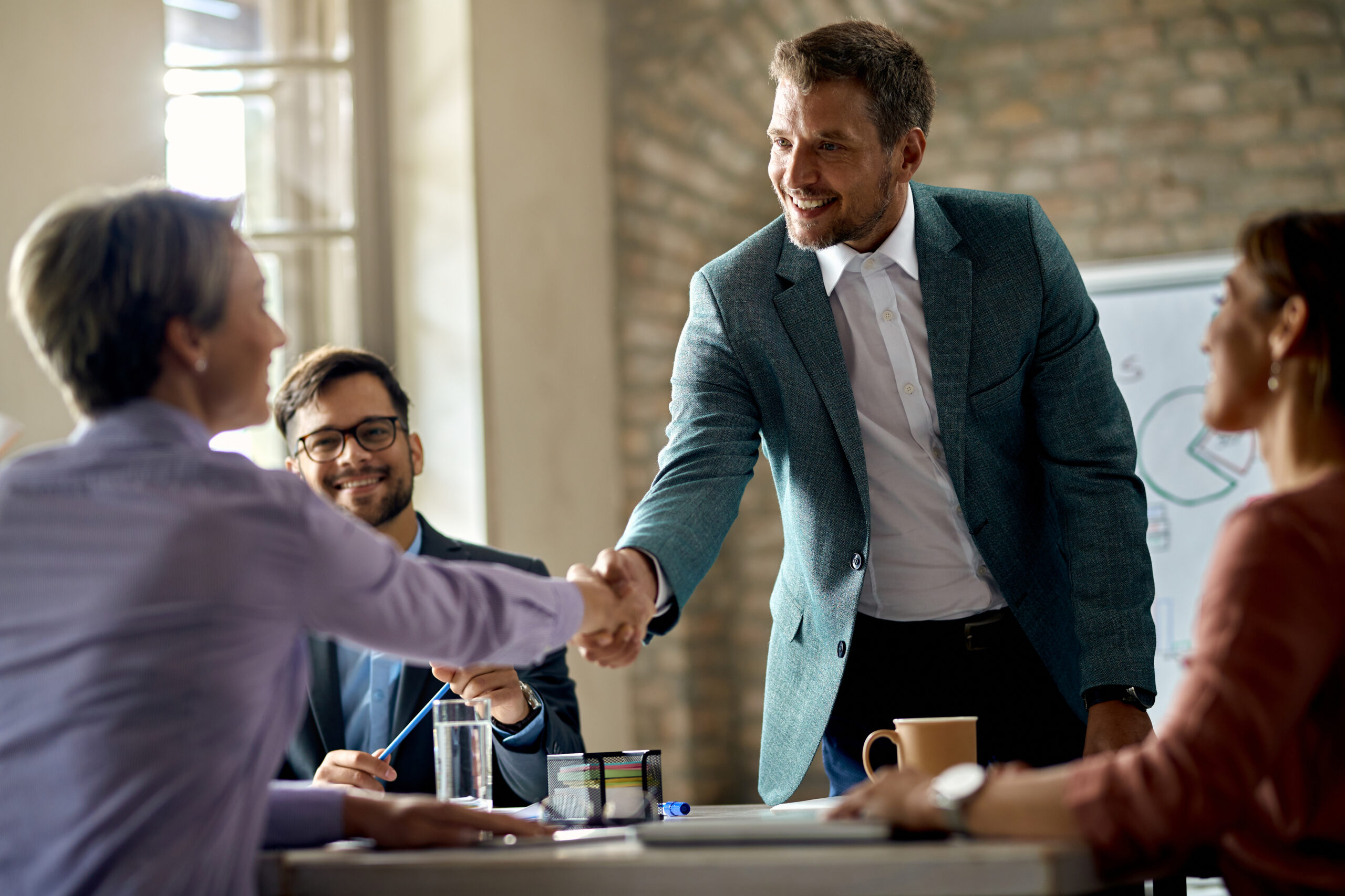 Happy businessman greeting a female colleague on a meeting in th
